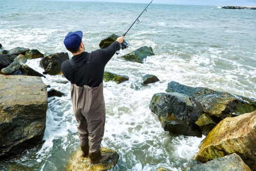 young-man-standing-on-rock-sea-fishing.jpg